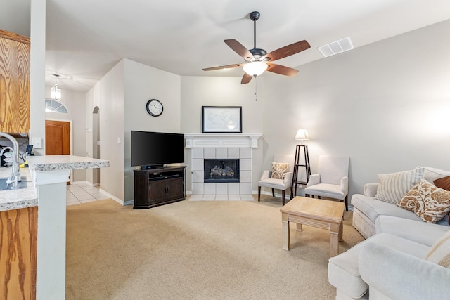 3601 Carmel Mountain Dr, Mckinney, TX 75070 - living room featuring light colored carpet, a ceiling fan, a tile fireplace, arched walkways, and baseboards