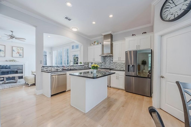 513 Suncreek Dr, Allen, TX 75013 - kitchen featuring stainless steel appliances, wall chimney exhaust hood, light wood finished floors, backsplash, and crown molding