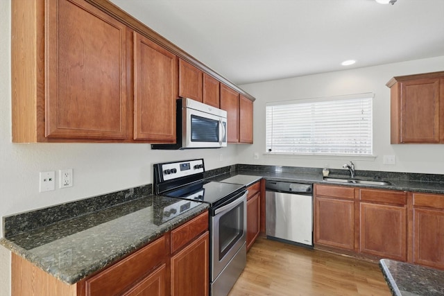 10748 Irish Glen Trl, Fort Worth, TX 76052 - kitchen featuring appliances with stainless steel finishes, a sink, light wood-style floors, brown cabinets, and dark stone countertops