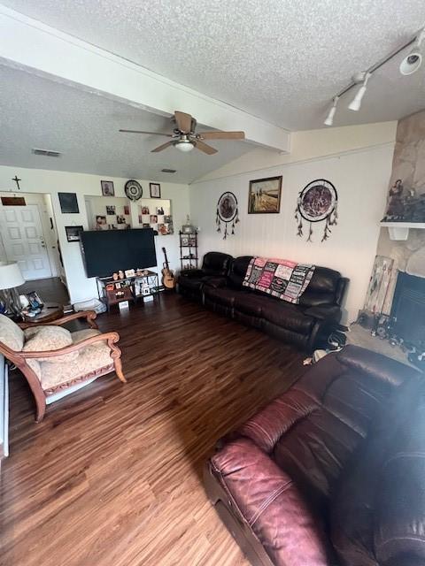 living area featuring a textured ceiling, a ceiling fan, wood finished floors, and a fireplace
