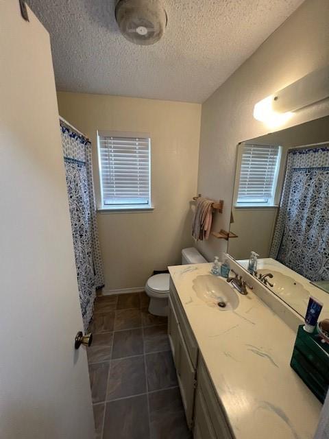 full bathroom featuring a textured ceiling, toilet, vanity, baseboards, and curtained shower