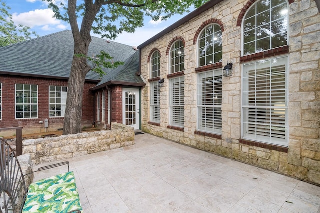1201 Tralee Ln, Garland, TX 75044 - rear view of house featuring a shingled roof, a patio, stone siding, and brick siding