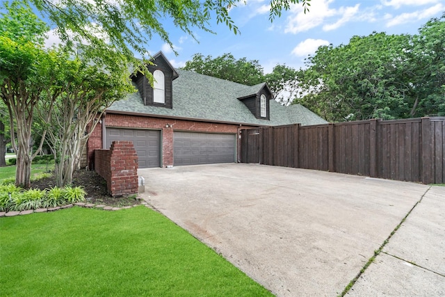 1201 Tralee Ln, Garland, TX 75044 - view of home's exterior with a shingled roof, driveway, brick siding, and an attached garage