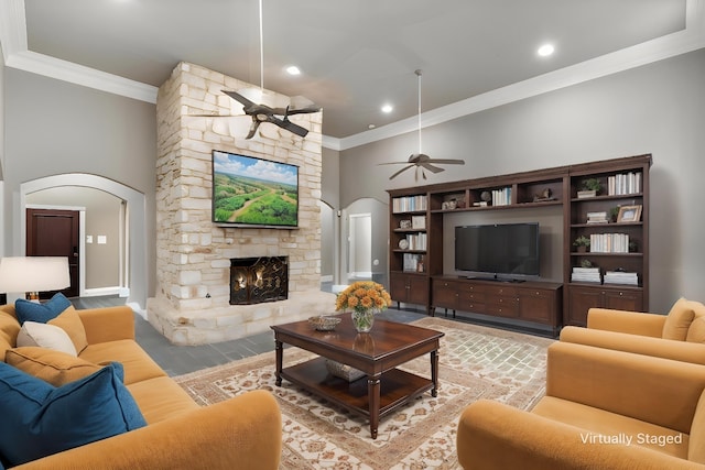 1201 Tralee Ln, Garland, TX 75044 - living area with arched walkways, crown molding, ceiling fan, a stone fireplace, and wood finished floors