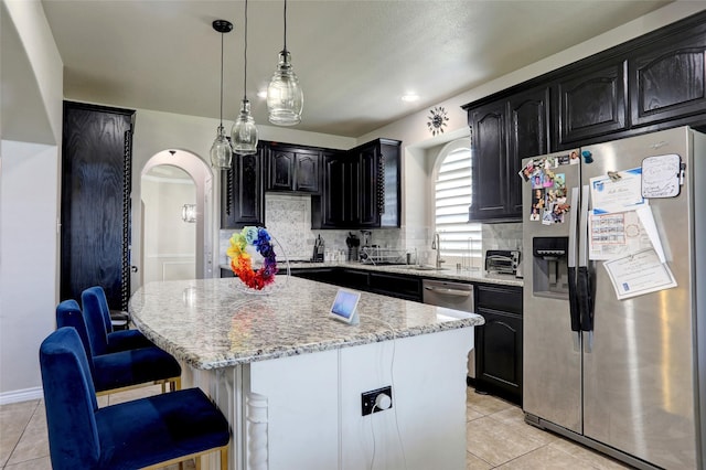 320 Trakehner Trl, Celina, TX 75009 - kitchen featuring stainless steel refrigerator with ice dispenser, light tile patterned flooring, a kitchen island, light stone countertops, and backsplash