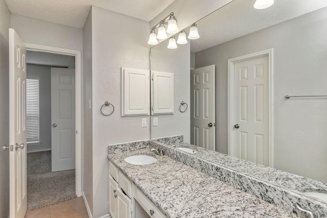 bathroom with vanity, a textured ceiling, tile patterned floors, and baseboards
