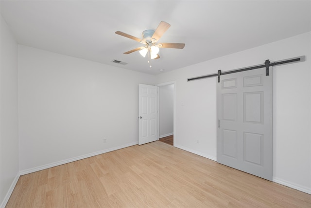 2320 Herring Ave, Waco, TX 76708 - unfurnished bedroom featuring a barn door, light wood finished floors, and baseboards