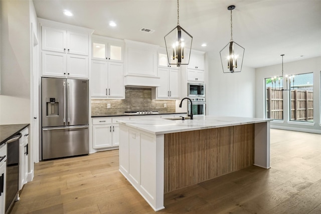 3621 Barber Crk, Fort Worth, TX 76244 - kitchen with appliances with stainless steel finishes, a chandelier, a sink, backsplash, and light wood-type flooring