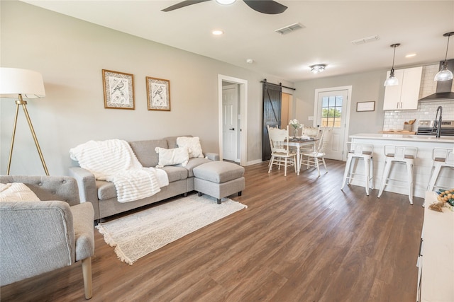 living room featuring a barn door, dark wood-style flooring, ceiling fan, recessed lighting, and baseboards