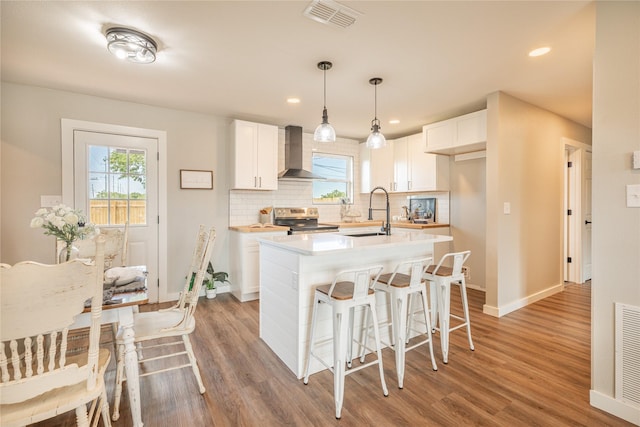 kitchen with wall chimney range hood, electric range, light wood finished floors, tasteful backsplash, and baseboards