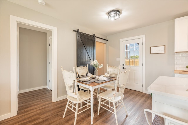 dining room with a barn door, wood finished floors, and baseboards