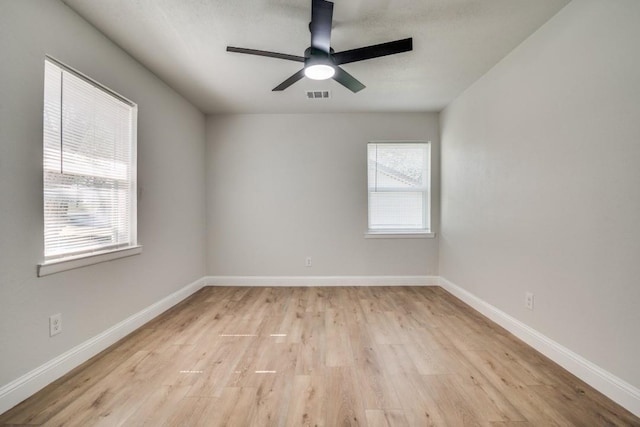 spare room with light wood-type flooring, a ceiling fan, and baseboards