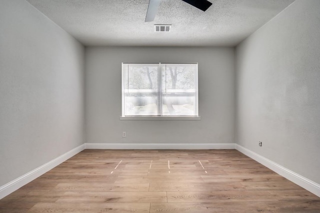 unfurnished room with a ceiling fan, a textured ceiling, light wood-type flooring, and baseboards