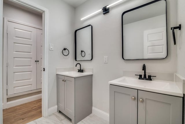 bathroom with two vanities, baseboards, and marble look tile flooring
