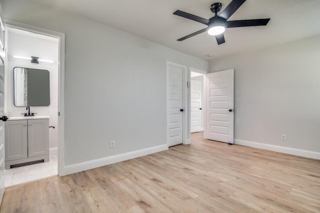 unfurnished bedroom with light wood-type flooring, baseboards, connected bathroom, and a sink