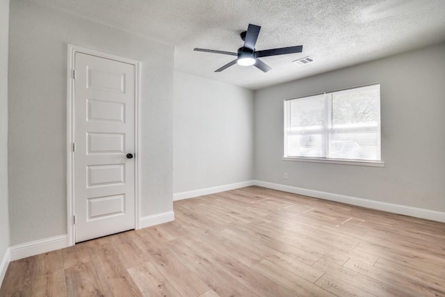 unfurnished room featuring light wood-style floors, a ceiling fan, a textured ceiling, and baseboards
