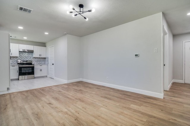 unfurnished living room with light wood-style flooring, a chandelier, baseboards, and recessed lighting