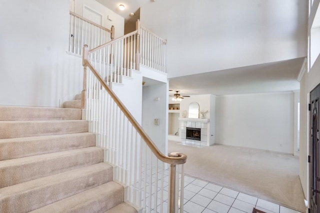 4136 Timberglen Rd, Dallas, TX 75287 - stairway with carpet, a towering ceiling, tile patterned flooring, a tiled fireplace, and a ceiling fan