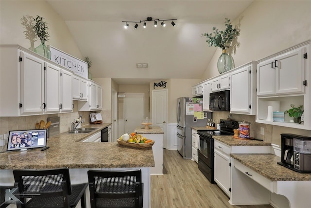 5249 Western Plains Ave, Abilene, TX 79606 - kitchen with black appliances, vaulted ceiling, a peninsula, white cabinetry, and decorative backsplash