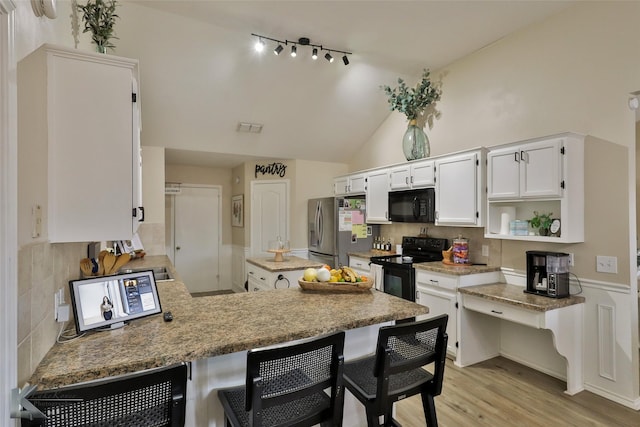 5249 Western Plains Ave, Abilene, TX 79606 - kitchen with black appliances, a peninsula, white cabinets, a breakfast bar, and tasteful backsplash