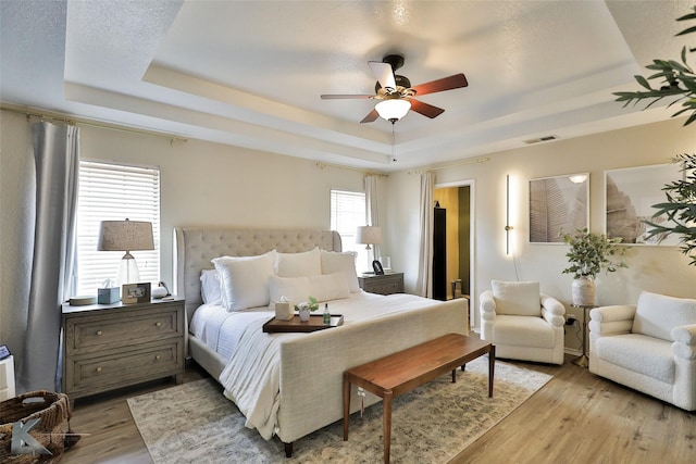 5249 Western Plains Ave, Abilene, TX 79606 - bedroom featuring a tray ceiling, light wood-type flooring, and ceiling fan