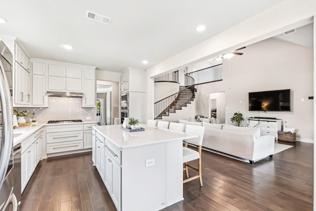 639 Cirrus Ln, Fate, TX 75087 - kitchen with dark wood-type flooring, gas cooktop, light countertops, white cabinets, and decorative backsplash