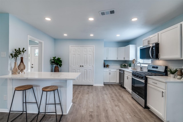 2335 San Paula Ave, Dallas, TX 75228 - kitchen featuring appliances with stainless steel finishes, a breakfast bar, a sink, white cabinets, and recessed lighting