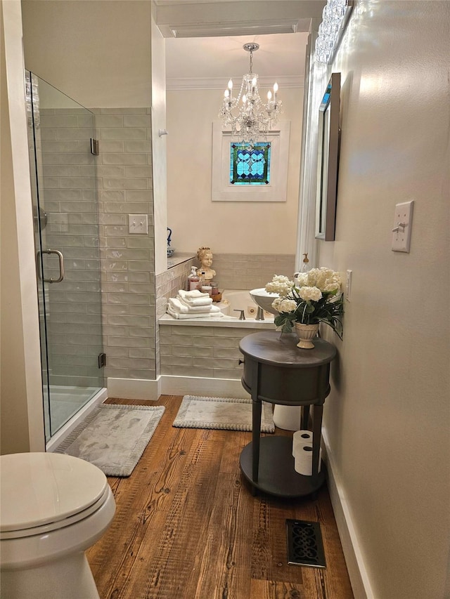 301 W Larissa St, Jacksonville, TX 75766 - bathroom with wood finished floors, a shower stall, a garden tub, baseboards, and a chandelier
