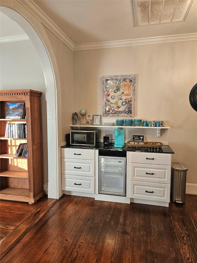 301 W Larissa St, Jacksonville, TX 75766 - bar with beverage cooler, dark wood-style flooring, black microwave, ornamental molding, and arched walkways