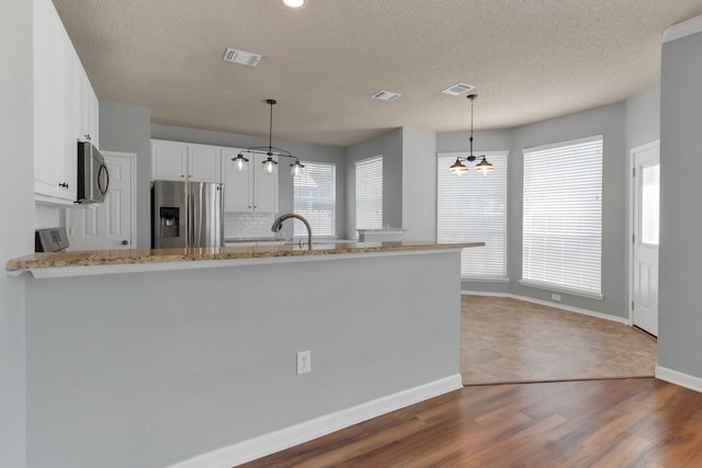 4504 Angelina Way, Fort Worth, TX 76137 - kitchen featuring stainless steel appliances, a chandelier, light stone countertops, white cabinets, and a peninsula