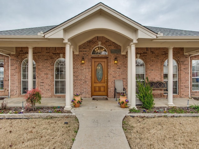 503 Hillcrest Ln, Krum, TX 76249 - view of exterior entry with a shingled roof, covered porch, and brick siding