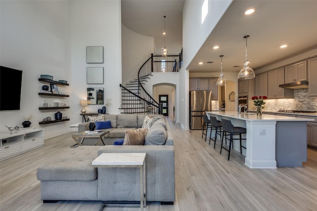 3229 Creek Meadow Dr, Anna, TX 75409 - living area featuring stairway, light wood finished floors, a high ceiling, arched walkways, and recessed lighting