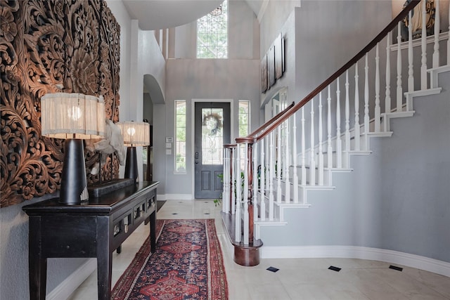 1217 Waterford Way, Allen, TX 75013 - tiled entryway with arched walkways, baseboards, stairs, a towering ceiling, and a wood stove