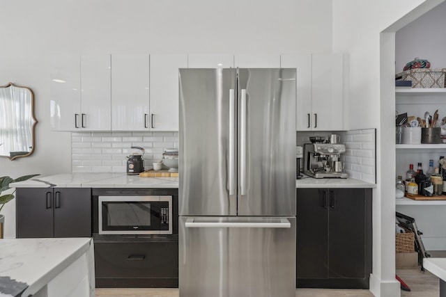 2102 N Prairie Ave Unit 105, Dallas, TX 75204 - kitchen with appliances with stainless steel finishes, tasteful backsplash, white cabinetry, light stone countertops, and modern cabinets