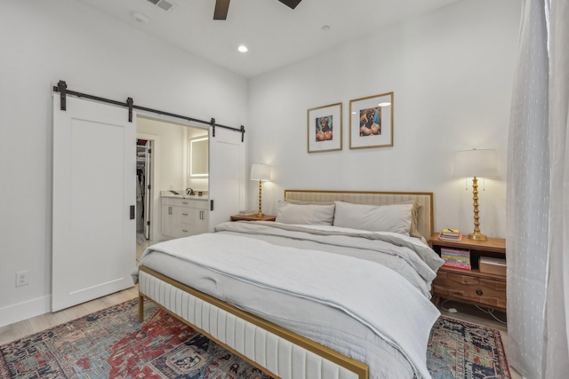 2102 N Prairie Ave Unit 105, Dallas, TX 75204 - bedroom with a barn door, wood finished floors, baseboards, recessed lighting, and connected bathroom