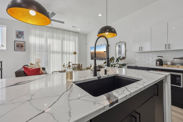 2102 N Prairie Ave Unit 105, Dallas, TX 75204 - kitchen featuring a sink, hanging light fixtures, backsplash, light stone countertops, and white cabinets