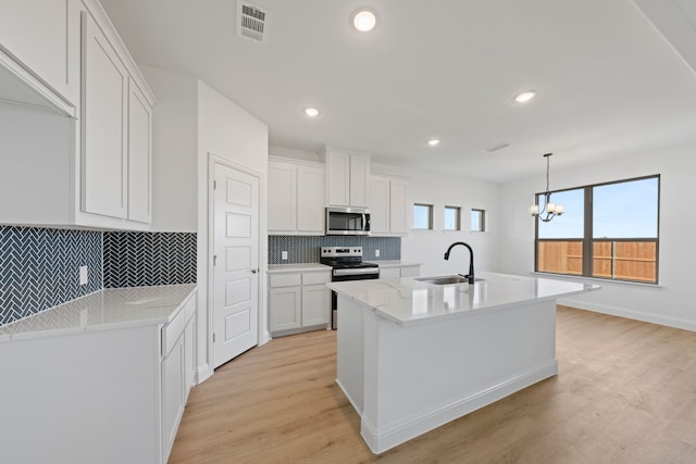 kitchen featuring a sink, appliances with stainless steel finishes, light wood-style flooring, decorative backsplash, and white cabinetry
