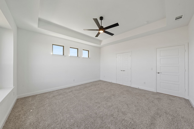 unfurnished bedroom featuring a tray ceiling, carpet floors, baseboards, and a ceiling fan