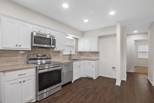 1201 Crockett St, Garland, TX 75040 - kitchen featuring appliances with stainless steel finishes, a sink, backsplash, white cabinetry, and dark wood-style floors