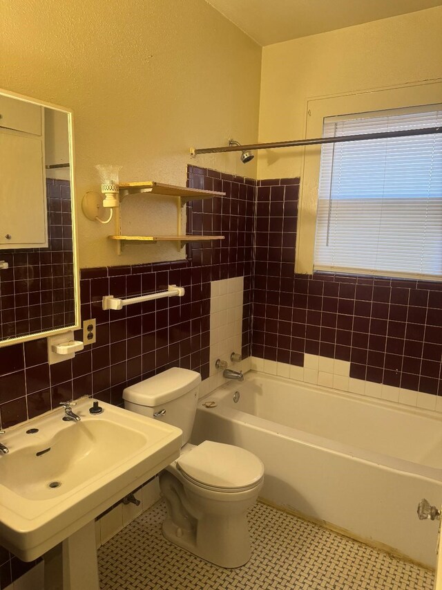 605 Merrick St, Shreveport, LA 71104 - full bathroom featuring tile walls, toilet, a wainscoted wall, shower / bathtub combination, and a sink