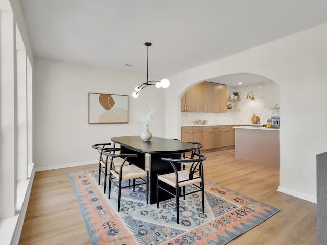 618 Berkley Dr, Grapevine, TX 76051 - dining room with arched walkways, light wood-style floors, baseboards, and a chandelier