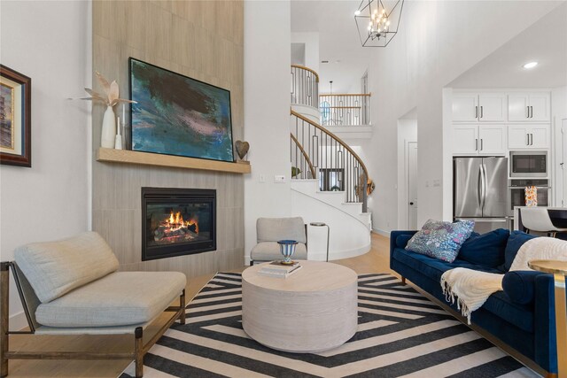 507 Melody Meadow Dr, Rockwall, TX 75087 - living area with stairway, a high ceiling, a fireplace, a chandelier, and wood finished floors
