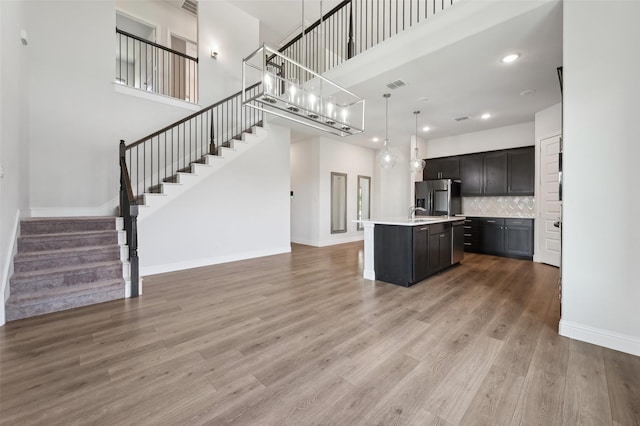 6322 Farndon Dr, Celina, TX 76227 - kitchen with a towering ceiling, fridge with ice dispenser, light countertops, an island with sink, and light wood finished floors