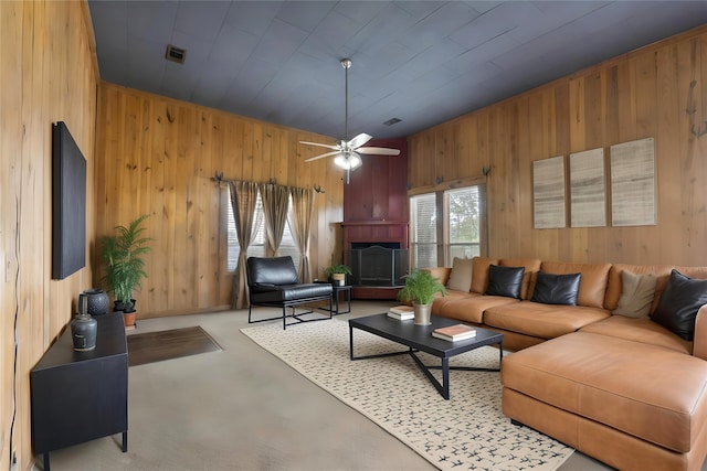 442 W Mccart St, Krum, TX 76249 - living room with wood walls, a fireplace with raised hearth, a ceiling fan, and light colored carpet