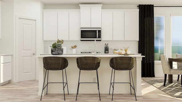 804 Enys Rd, Mckinney, TX 75069 - kitchen featuring stainless steel microwave, backsplash, light countertops, white cabinetry, and a kitchen island with sink