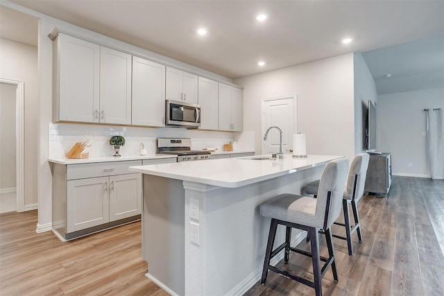 2148 Bellatrix Dr, Haslet, TX 76052 - kitchen featuring stainless steel appliances, a sink, a center island with sink, light wood-style floors, and backsplash