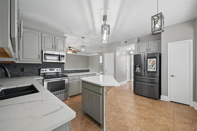 3211 Ruidoso Ln, Mckinney, TX 75070 - kitchen with appliances with stainless steel finishes, gray cabinetry, tasteful backsplash, a center island, and ceiling fan
