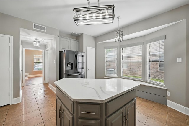 3211 Ruidoso Ln, Mckinney, TX 75070 - kitchen with stainless steel fridge with ice dispenser, gray cabinetry, light tile patterned flooring, a kitchen island, and baseboards