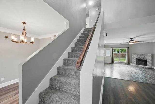 3211 Ruidoso Ln, Mckinney, TX 75070 - stairs featuring wood finished floors, a ceiling fan, a brick fireplace, baseboards, and a chandelier