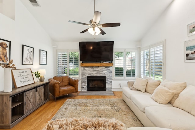 569 Dove Creek Cir, Grapevine, TX 76051 - living room featuring vaulted ceiling, light wood-style floors, a stone fireplace, healthy amount of natural light, and a ceiling fan